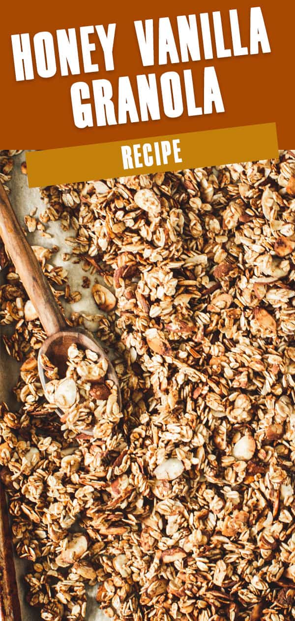 Honey vanilla granola on a baking sheet with a wooden spoon.