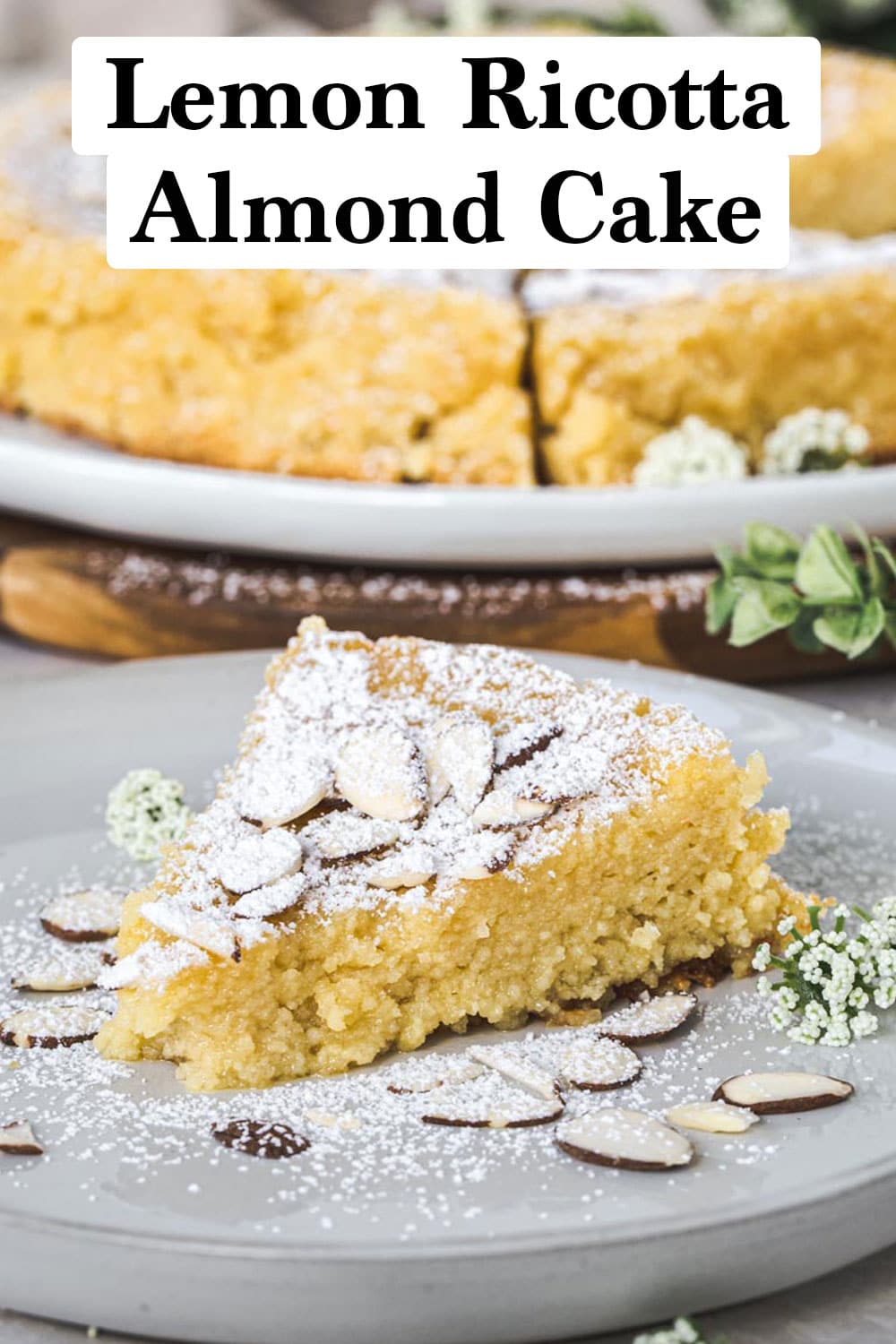 Slice of lemon ricotta almond cake dusted with powdered sugar on a white plate.