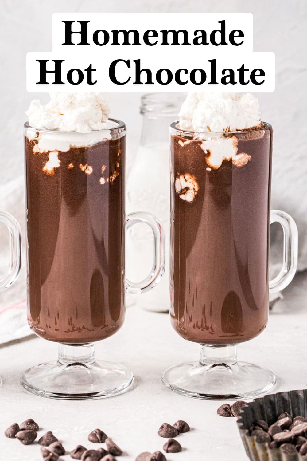 Homemade hot chocolate topped with homemade whipped cream in tall glasses with handles.