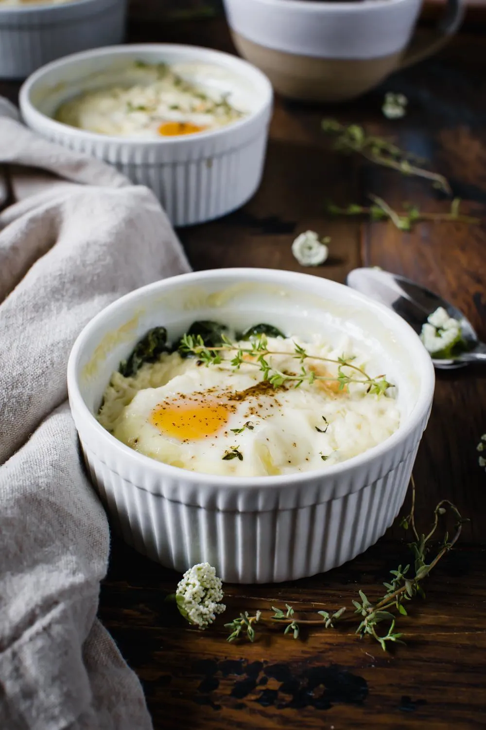 baked eggs with ricotta and thyme in white ramekin next to napkin