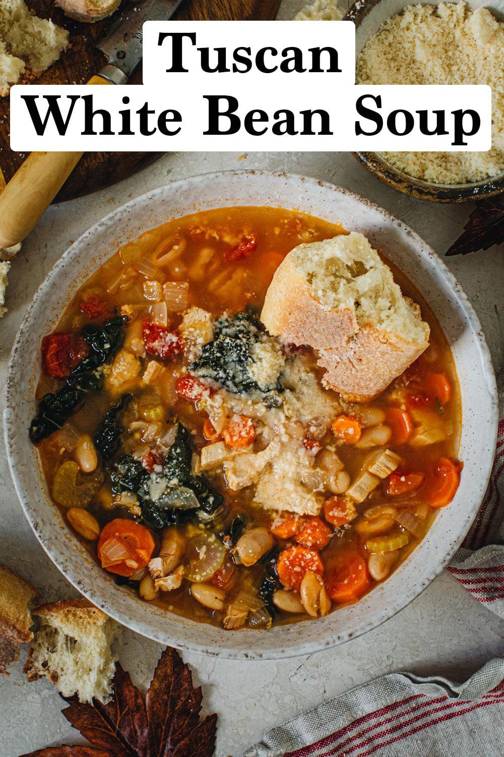 Tuscan white bean soup with crusty bread on top in a bowl.