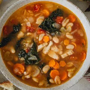 Tuscan white bean soup in a white bowl.