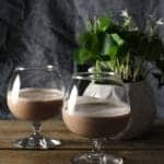 homemade butter pecan Irish cream in two small brandy glasses on wooden table.