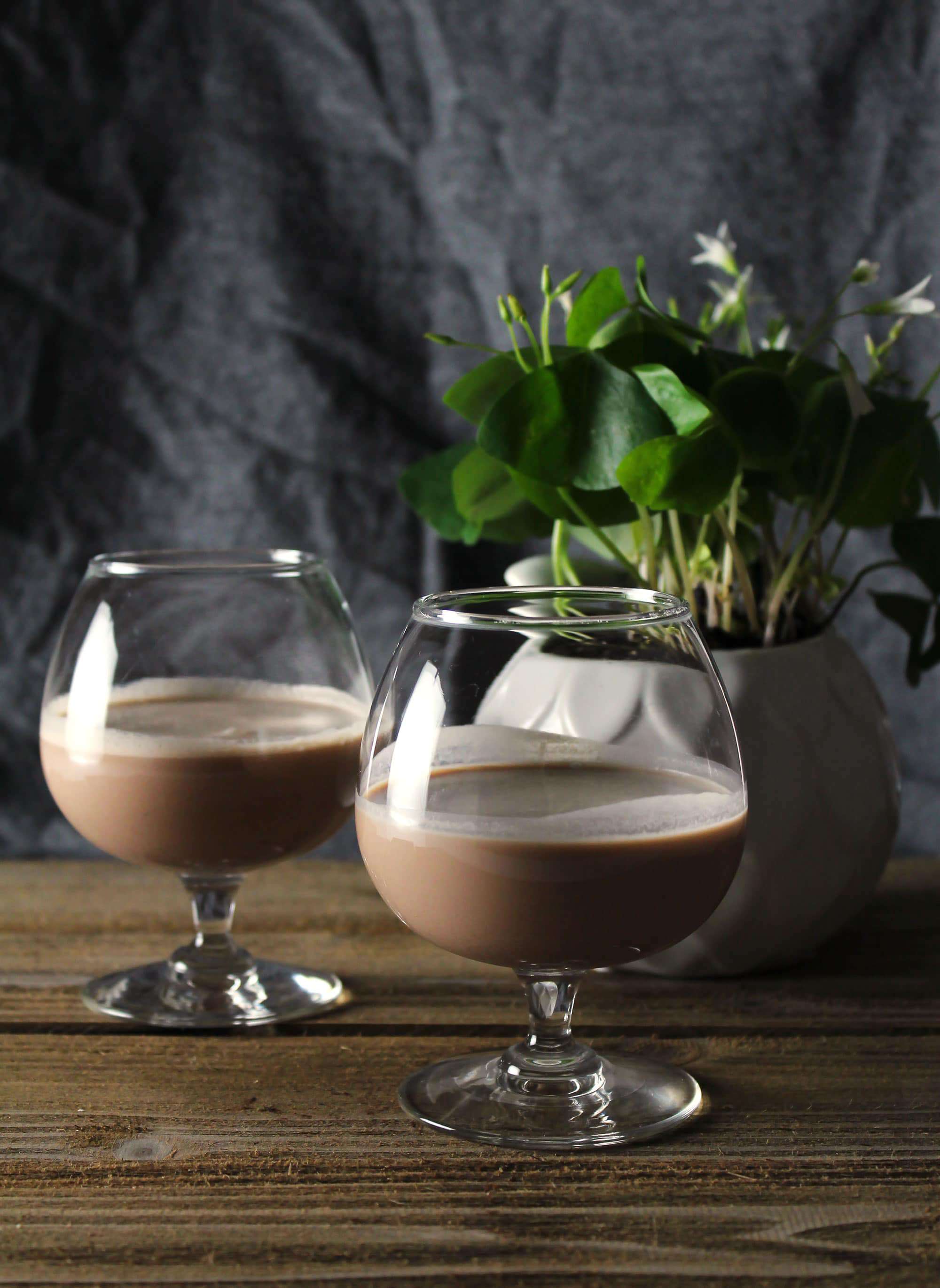 homemade butter pecan Irish cream in two small brandy glasses on wooden table.