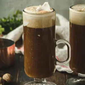 Vegan Irish coffee topped with coconut cream in a tall glass with a handle.