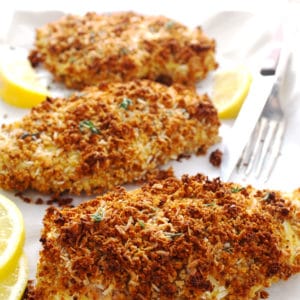 Breaded coconut chicken with lemon wedges surrounding it.