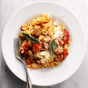 Sausage Pasta Pomodoro in a white bowl with two forks.