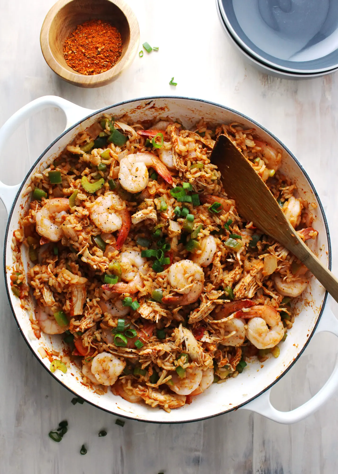 jambalaya in a white skillet with wooden spoon