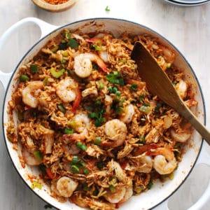 jambalaya in a white skillet with wooden spoon