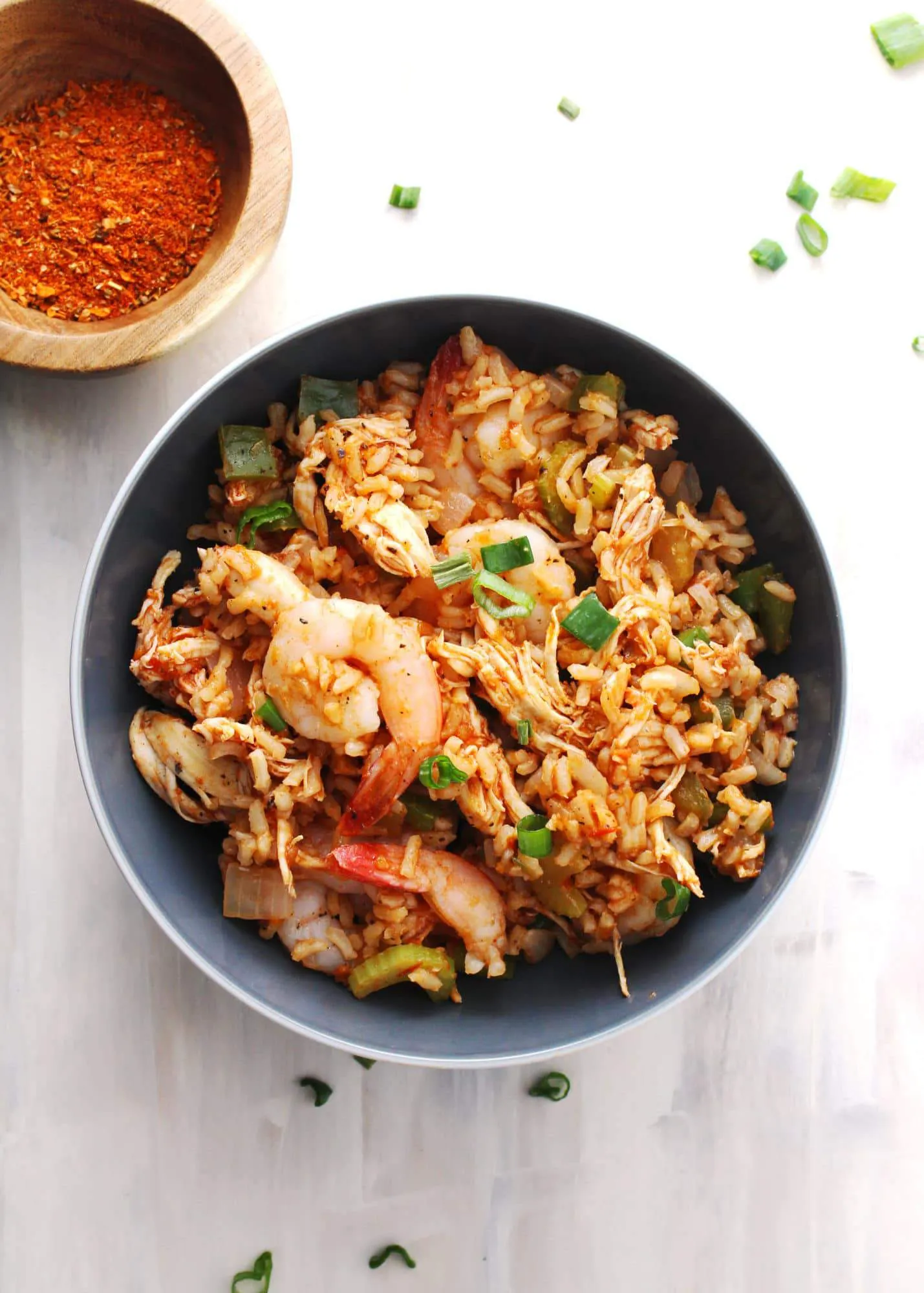 jambalaya in gray bowl with cajun seasoning bowl