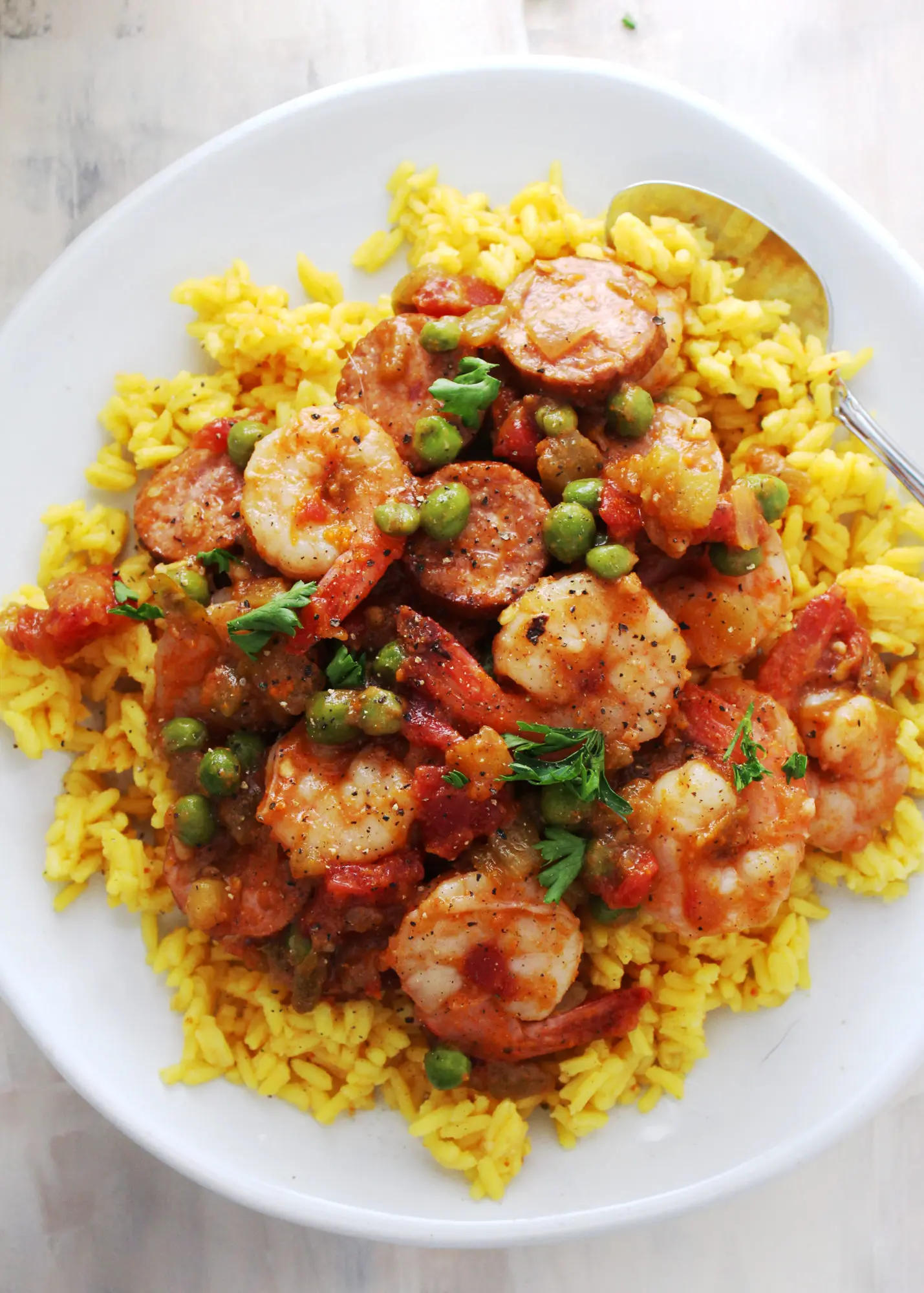 yellow rice topped with shrimp mixed with sausage and vegetables