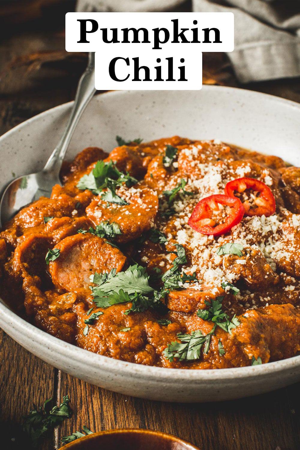 Pumpkin chili topped with cilantro and cheese in a white bowl.