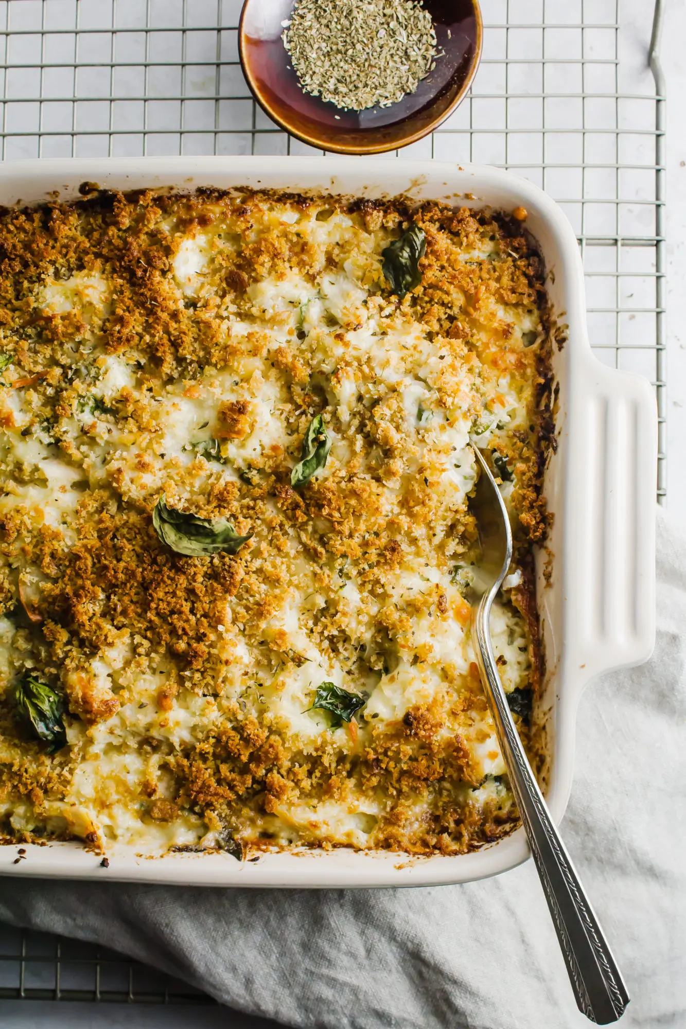 Chicken Alfredo Cauliflower Bake in a square casserole dish with a silver spoon inserted.