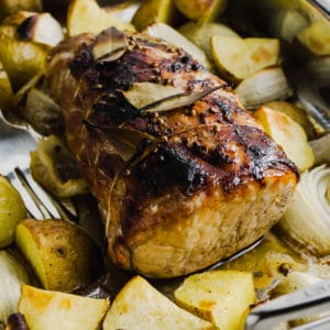 Cider brined pork roast with potatoes and onions surrounding it.