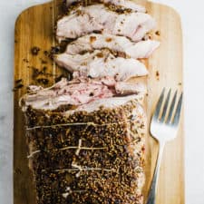 Roasted pork shoulder sliced on a cutting board.