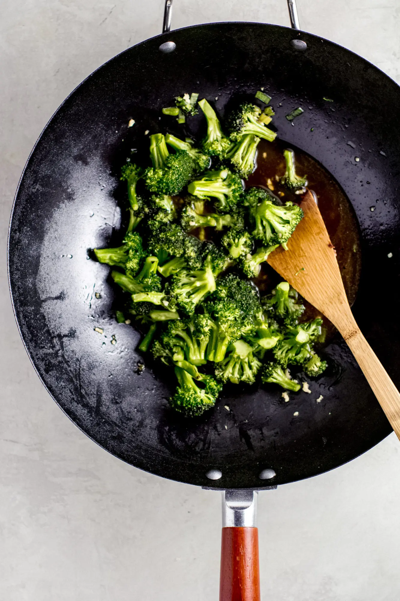 Stir fried broccoli in a wok with a wooden spatula