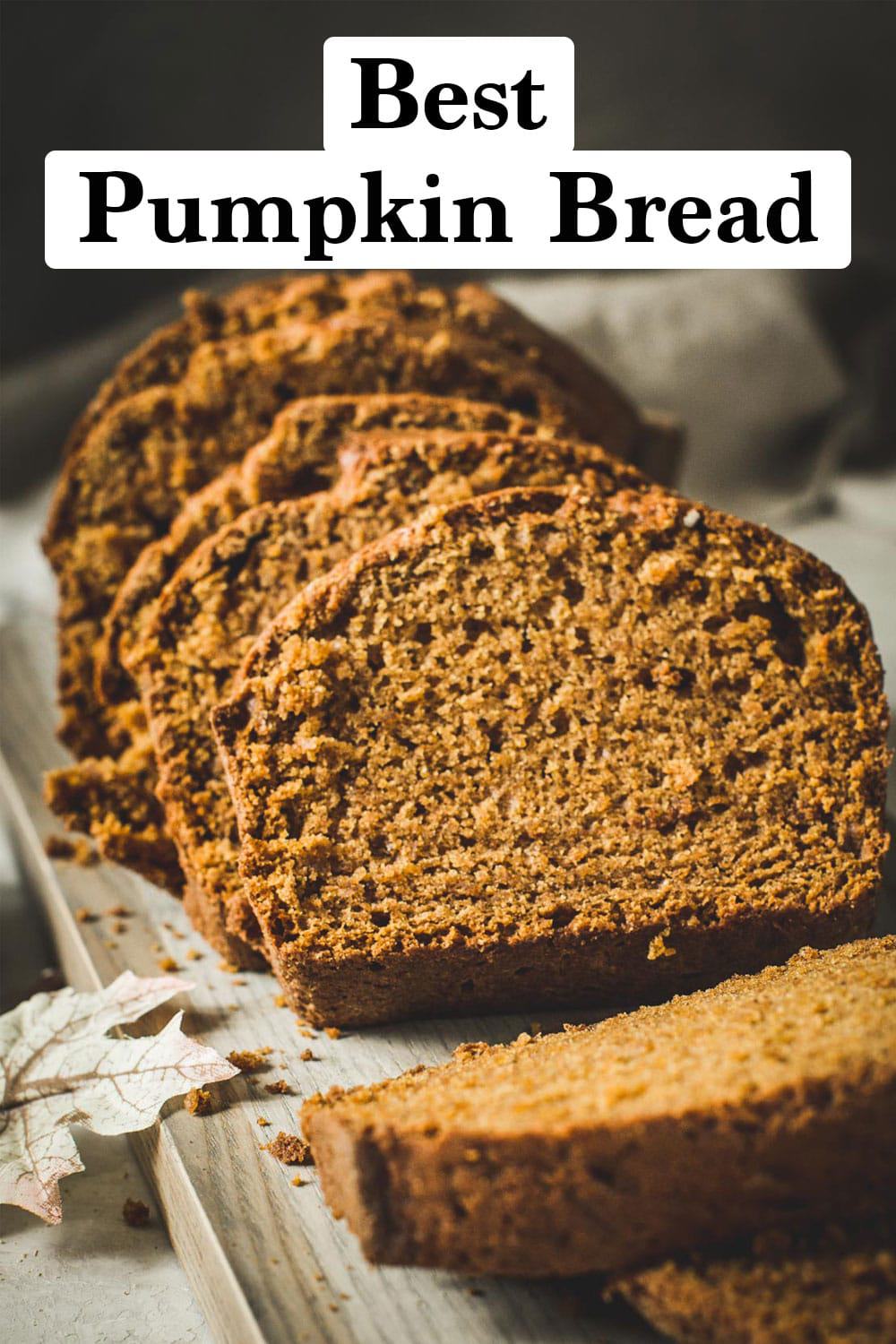 Moist pumpkin bread loaf sliced on a wooden cutting board.