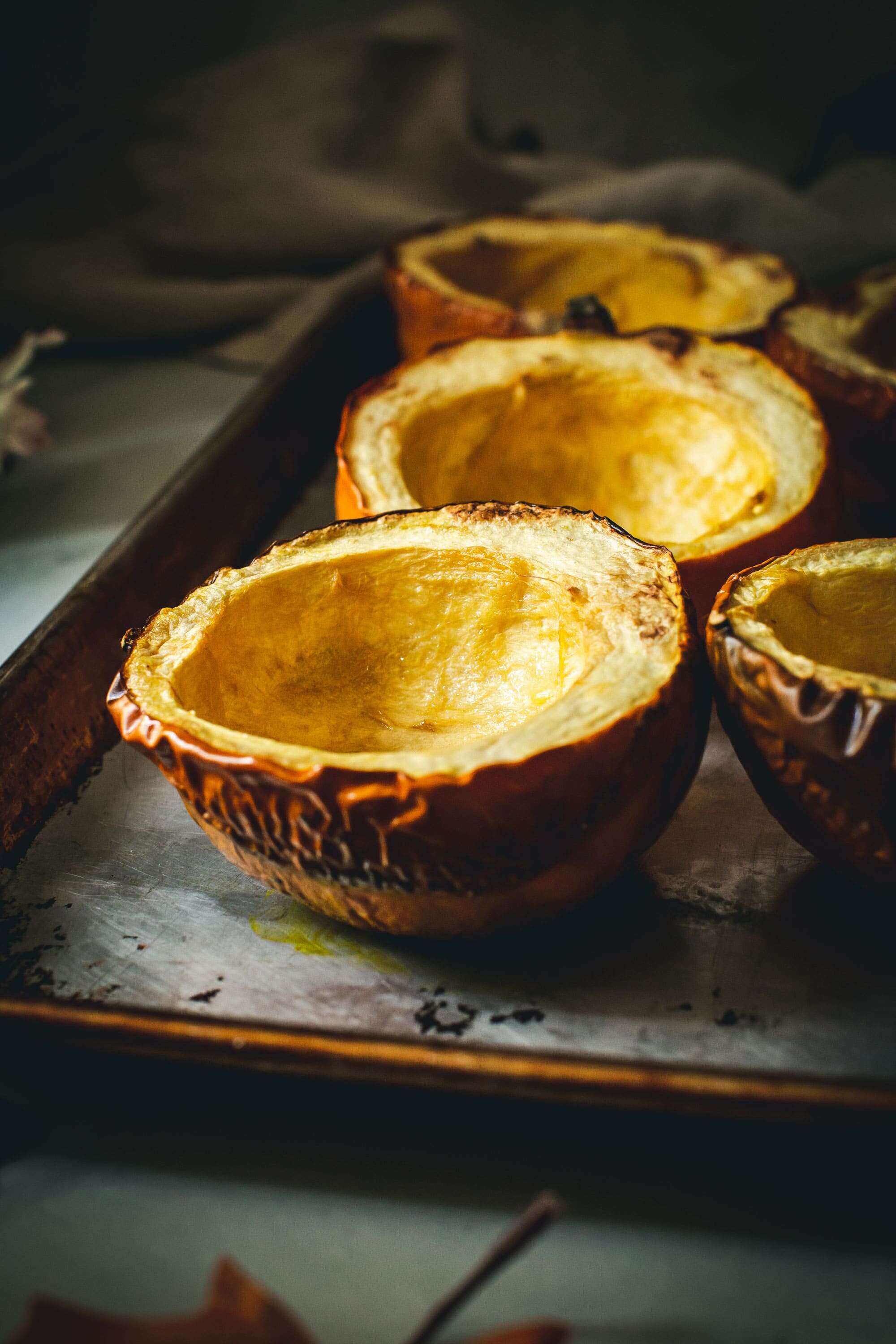 Halved and cooked acorn squash on a rimmed baking sheet.