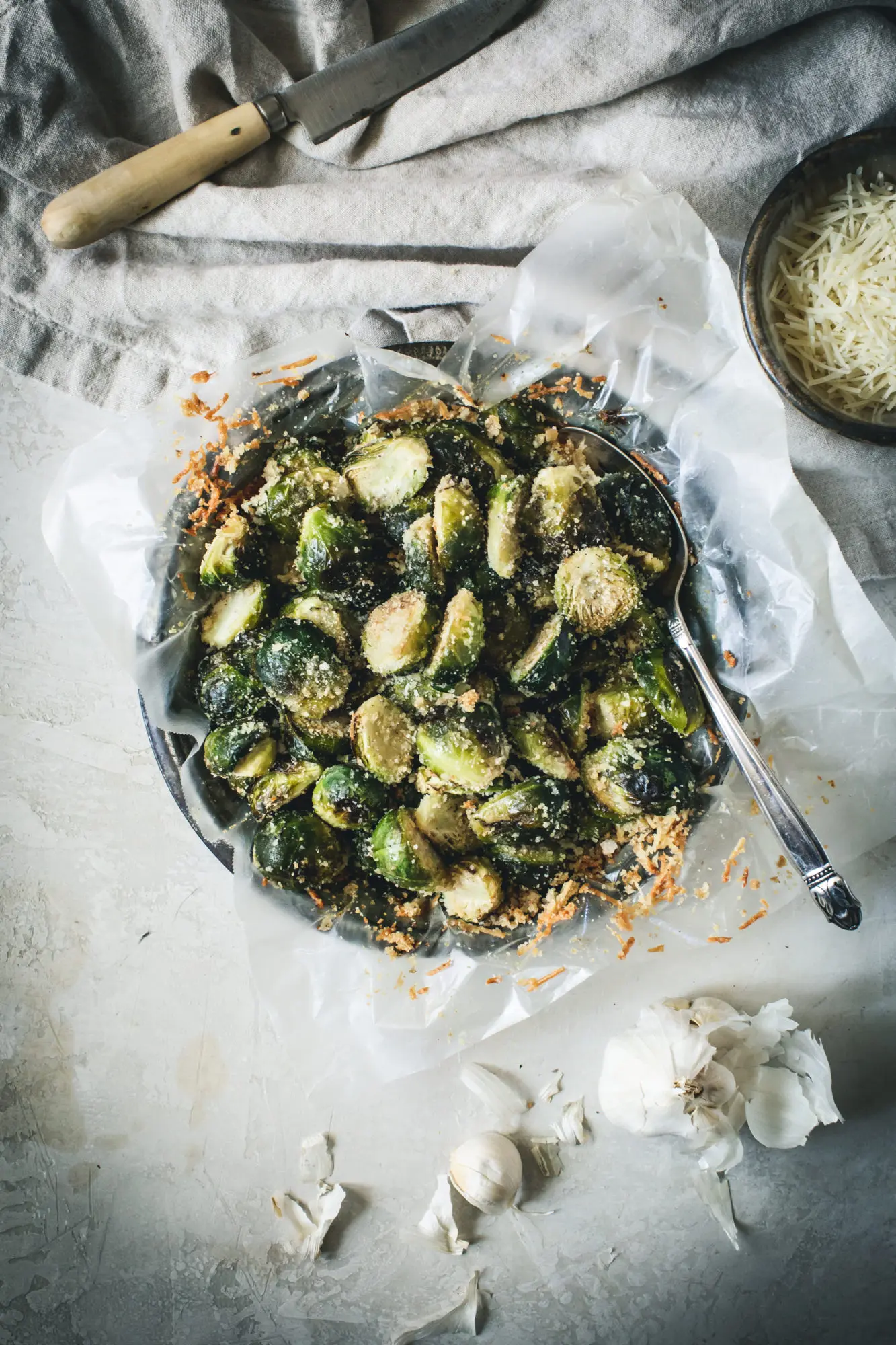 Roasted Brussel sprouts in a parchment covered tin with metal spoon