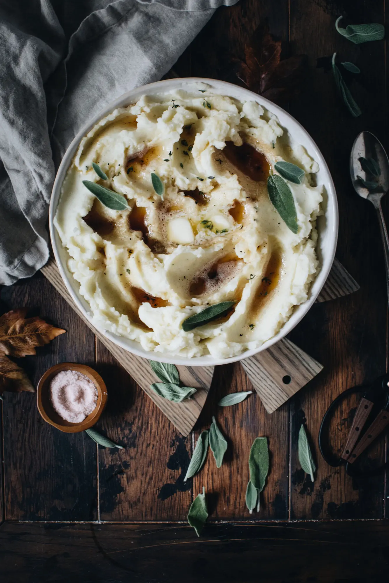 Brown butter garlic mashed potatoes in a bowl sitting on a cutting board.