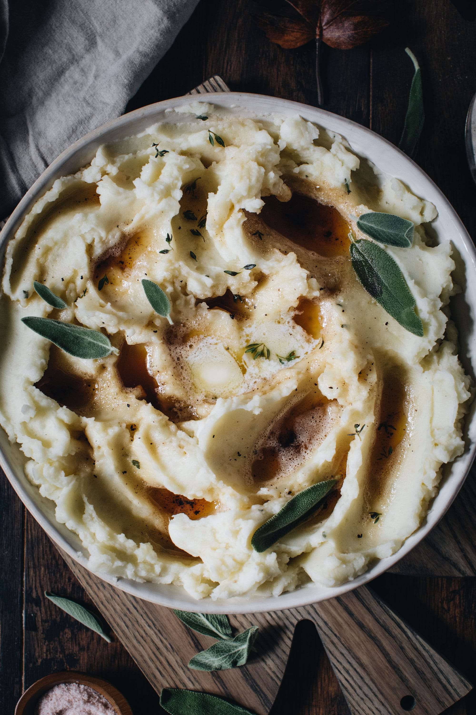 Brown butter mashed potatoes in a large bowl topped with fresh sage.