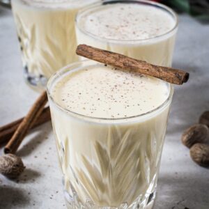 Eggnog in glasses topped with fresh nutmeg.