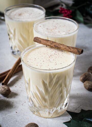 Eggnog in glasses topped with fresh nutmeg.