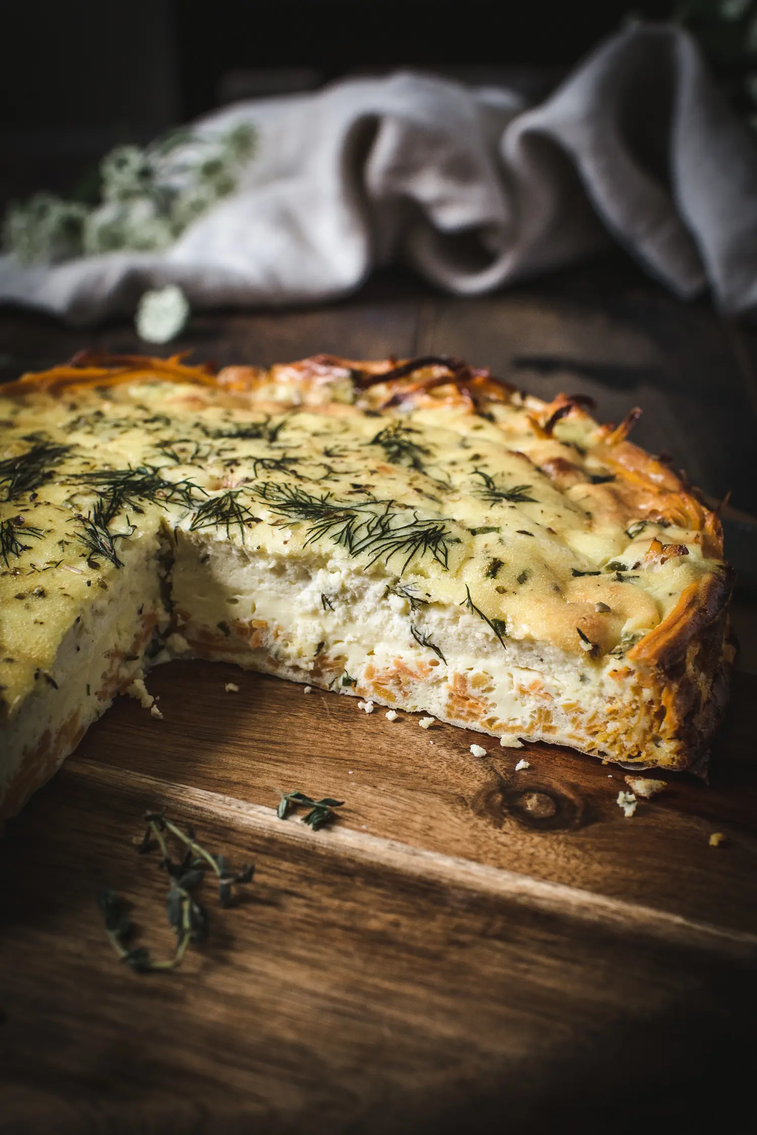 Goat cheese and herb quiche on a wooden board.