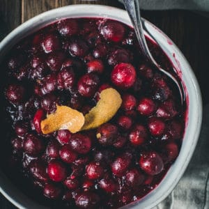 Bourbon cranberry sauce in a bowl topped with orange peel.