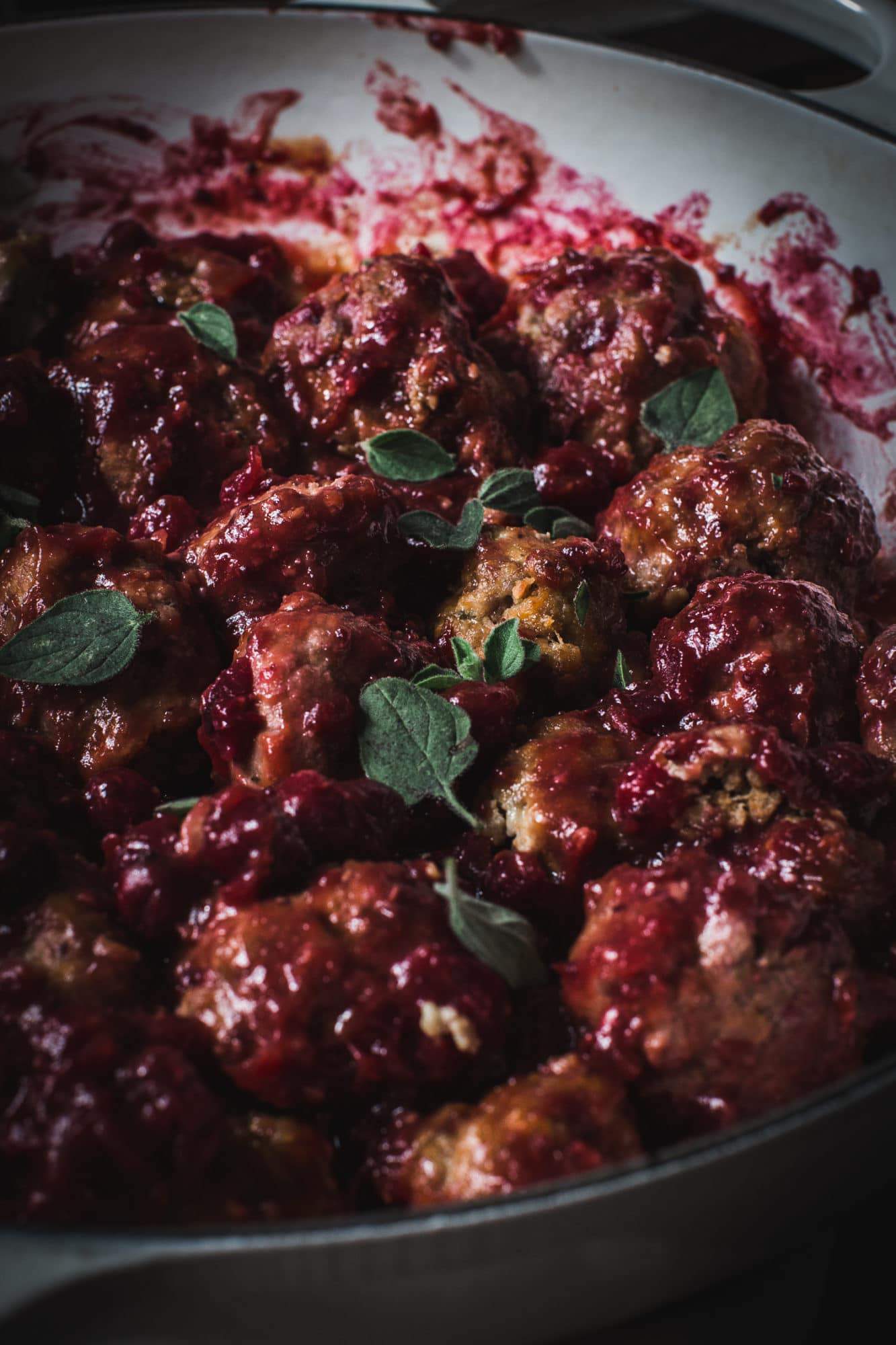 close up of cranberry meatballs with fresh oregano on top