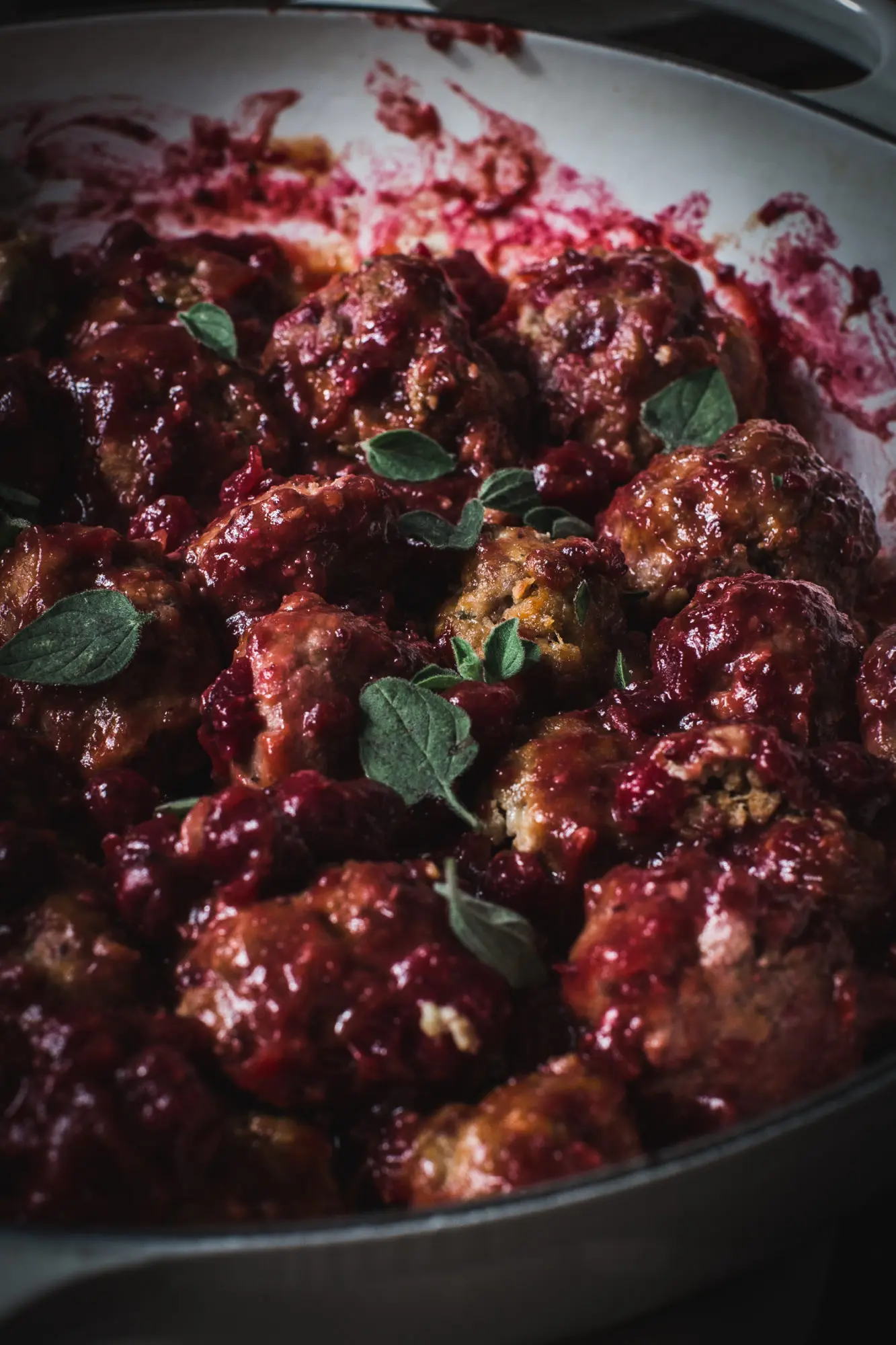close up of cranberry meatballs with fresh oregano on top