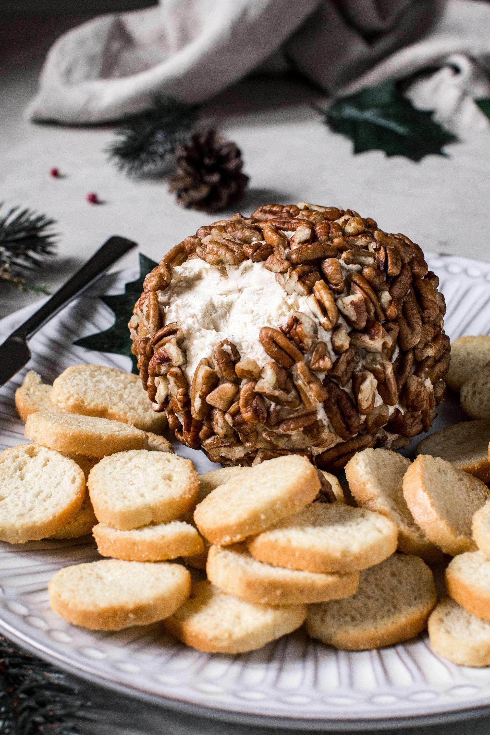 smoked cheese ball covered in pecans with crostini surrounding