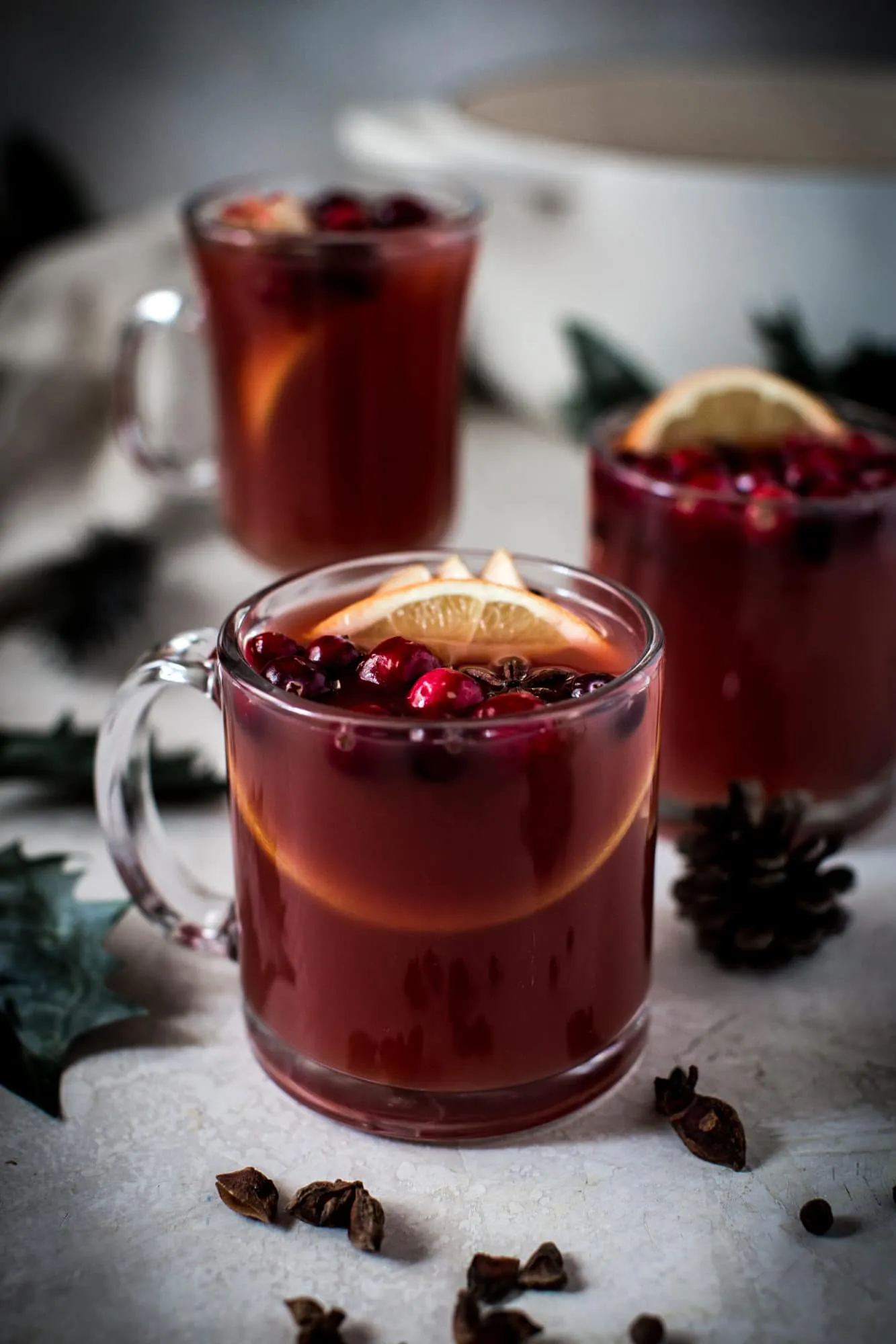 wassail in clear glass mugs with cranberries and orange slices