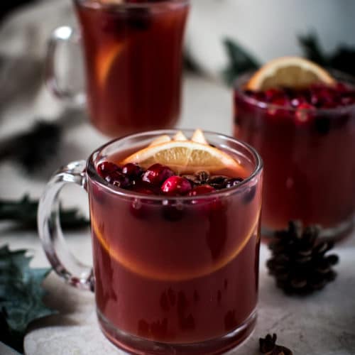 wassail in clear glass mugs with cranberries and orange slices