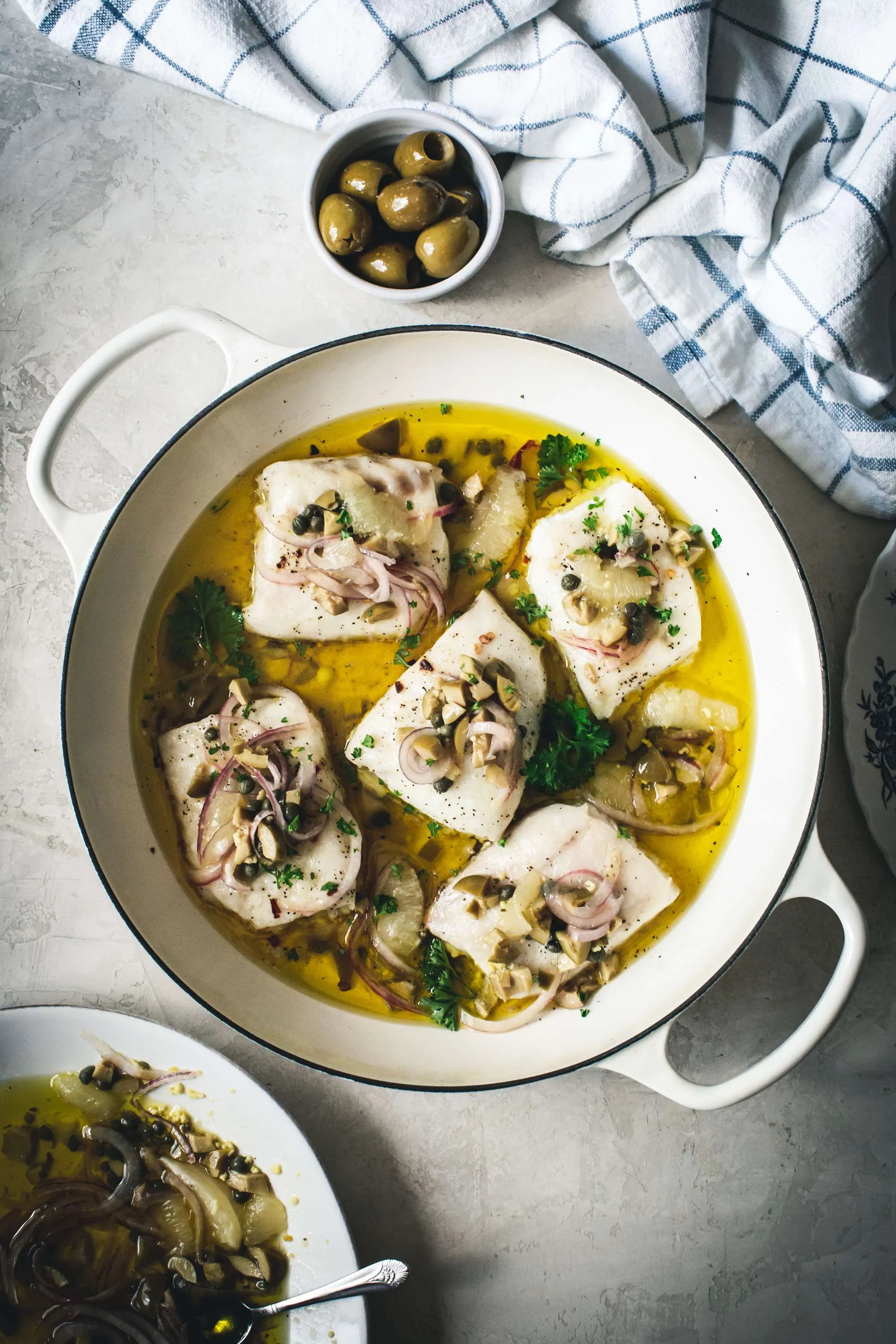 lemon baked cod in a white skillet with relish