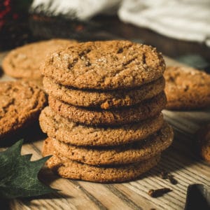 ginger molasses cookies stacked on a wooden cutting board