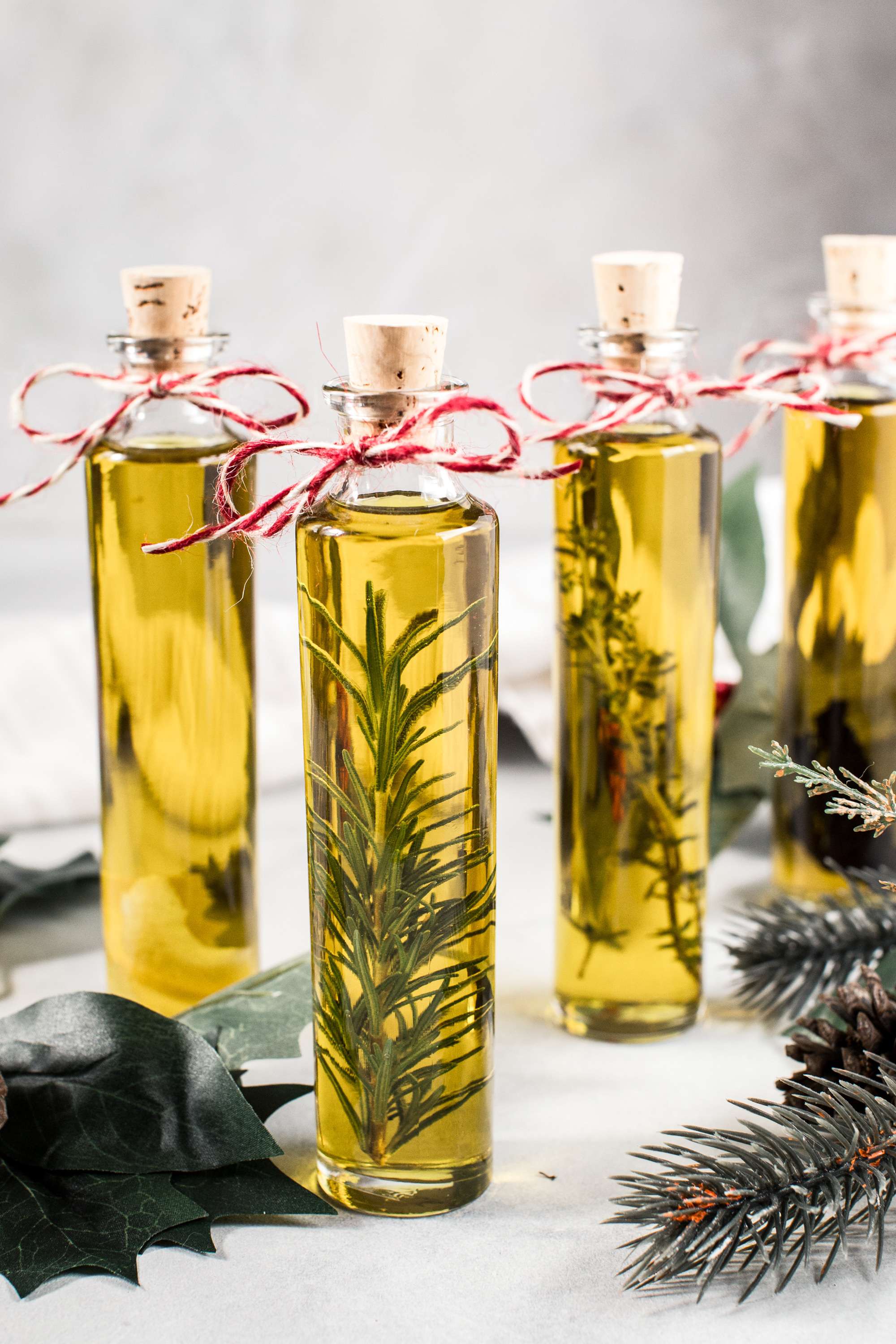 Infused olive oil recipes in tall glass jars with bakers twine tied around the neck.