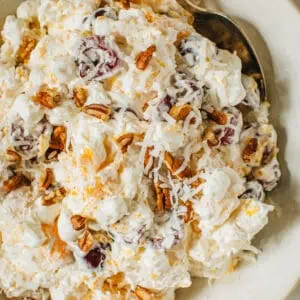 Ambrosia fruit salad in a bowl ready to serve with a spoon.