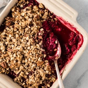 raspberry crisp in square dish with silver spoon scooping dessert out