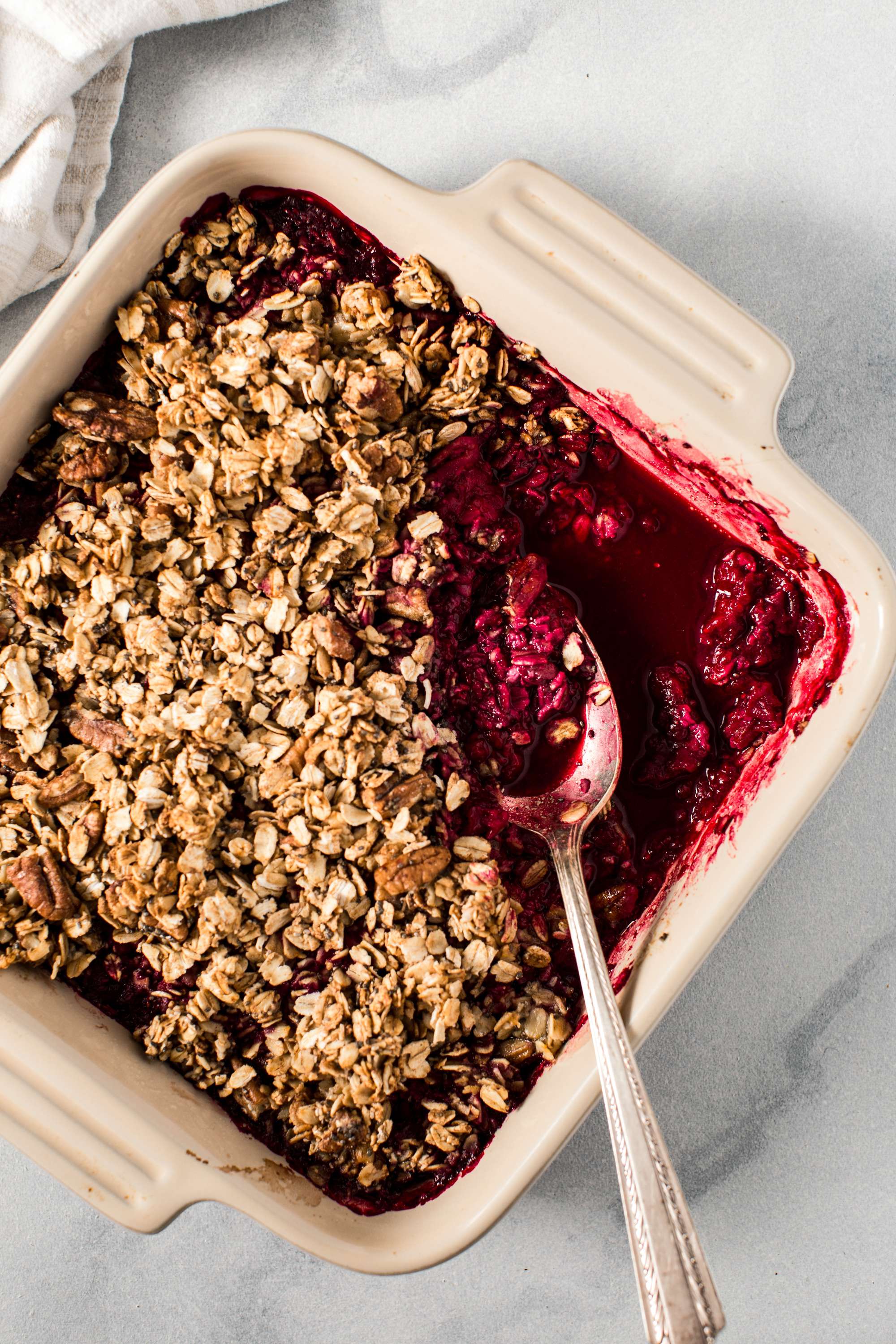 raspberry crisp in square dish with silver spoon scooping dessert out