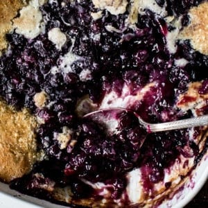 Close up of blueberry cobbler with a silver serving spoon.