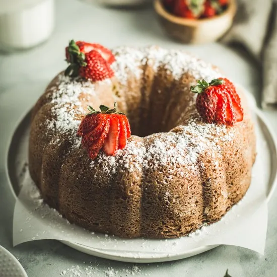 lemon ginger bundt cake topped with powdered sugar and sliced strawberries