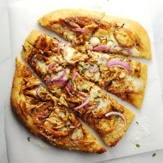 Buffalo chicken pizza sliced on parchment paper.