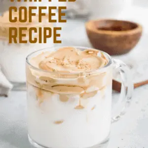 Whipped coffee in clear mug with brown and cream lettering.