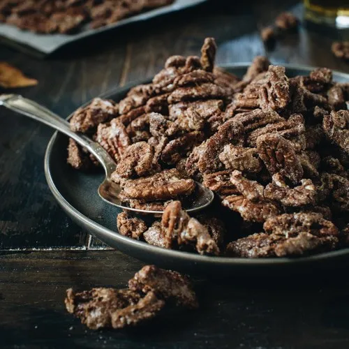 Cinnamon roasted pecans on a black plate.