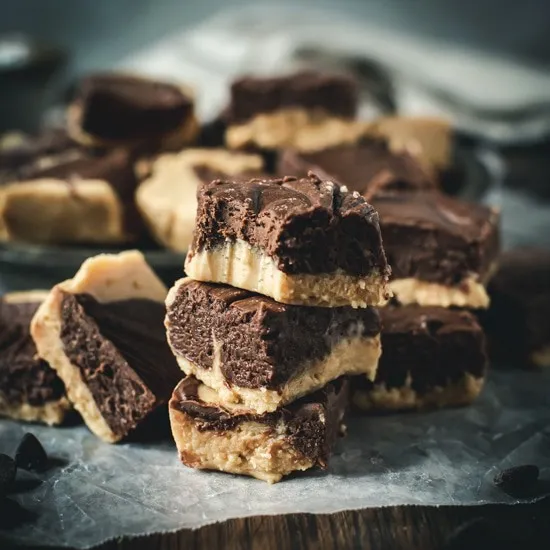 Squares of peanut butter chocolate fudge stacked.