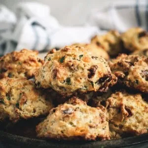 Cheddar drop biscuits stacked in a pan.