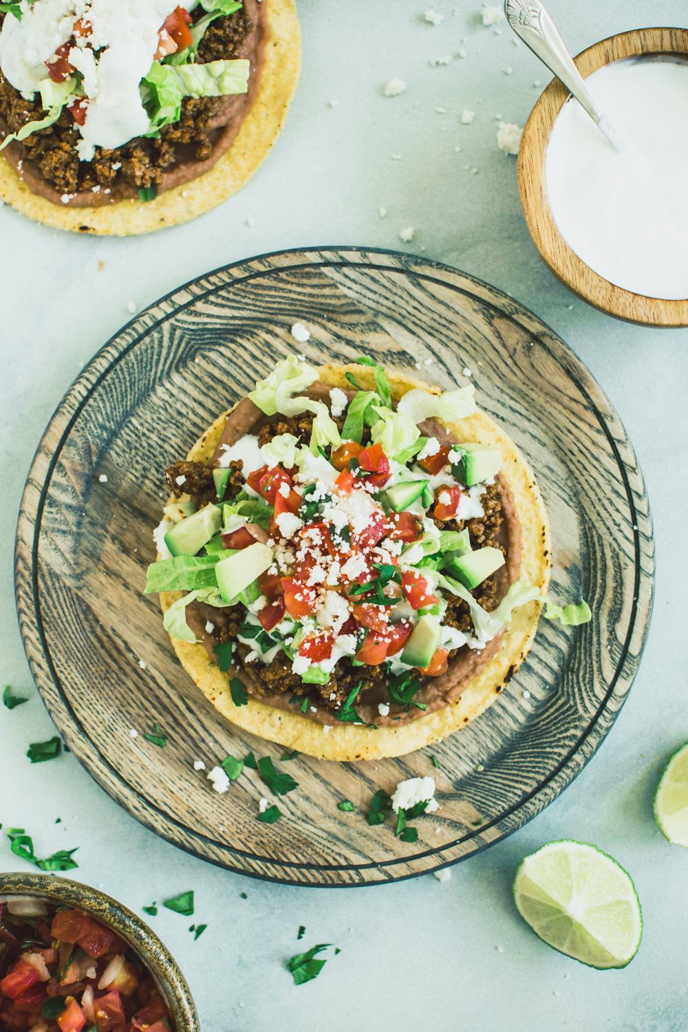 Ground beef tostada on a wooden plate.