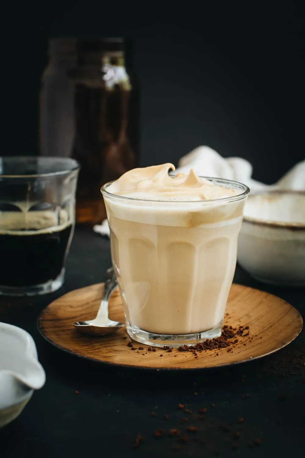 Indian cappuccino in a clear glass siting on a wooden plate