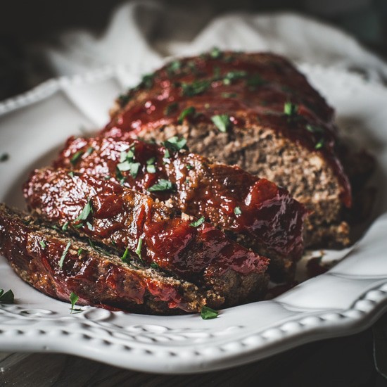 Slice meatloaf on a white serving platter.